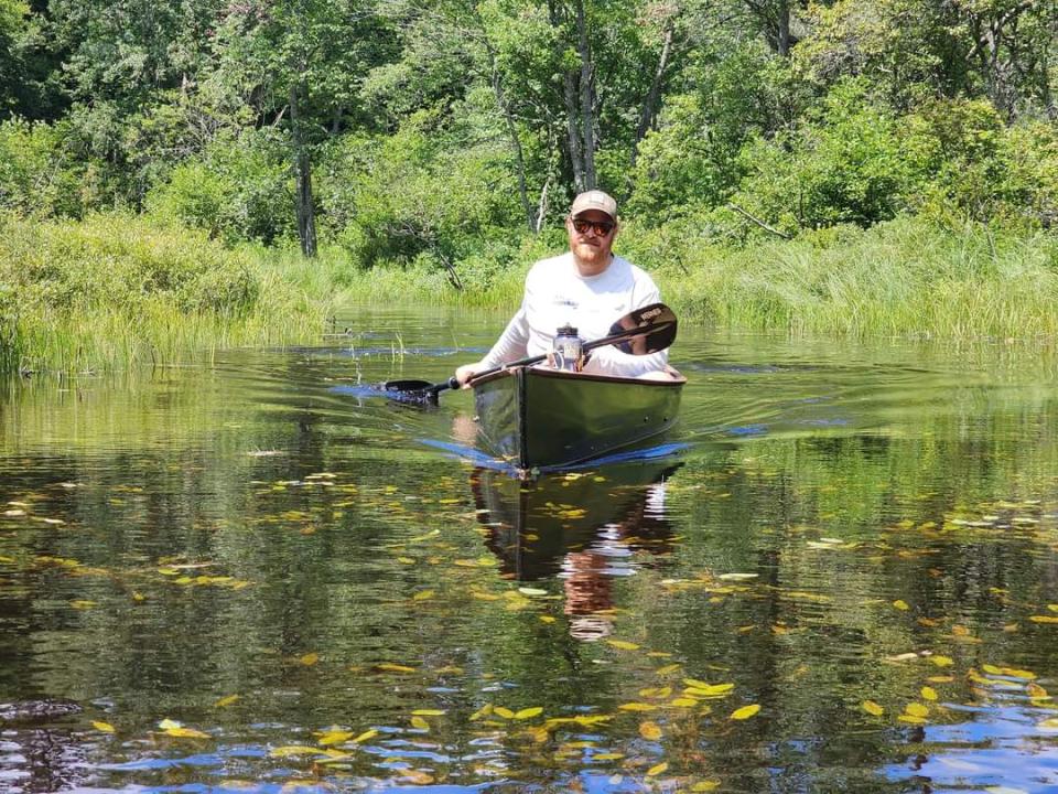 Man in black canoe paddling towards camera.