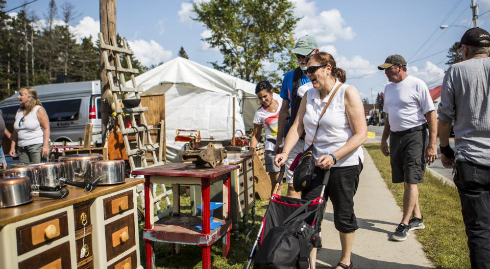 A woman pushes a stroller and browses antiques.