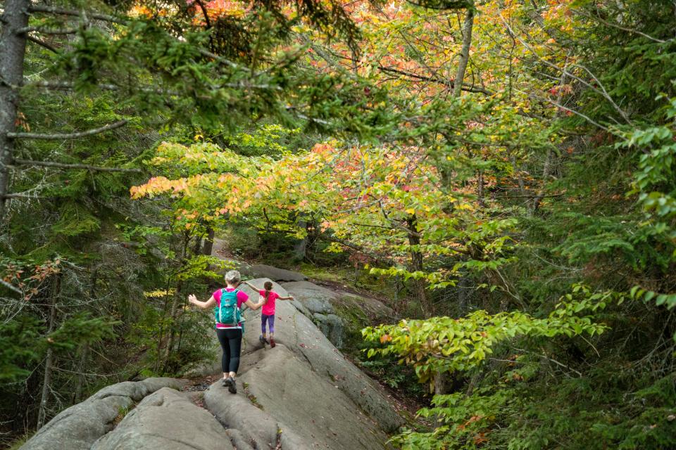 two children balance on rocks walking on a hike.