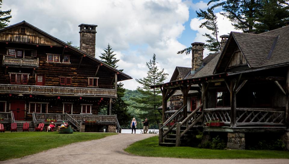 two people walk among giant log cabin lodges.