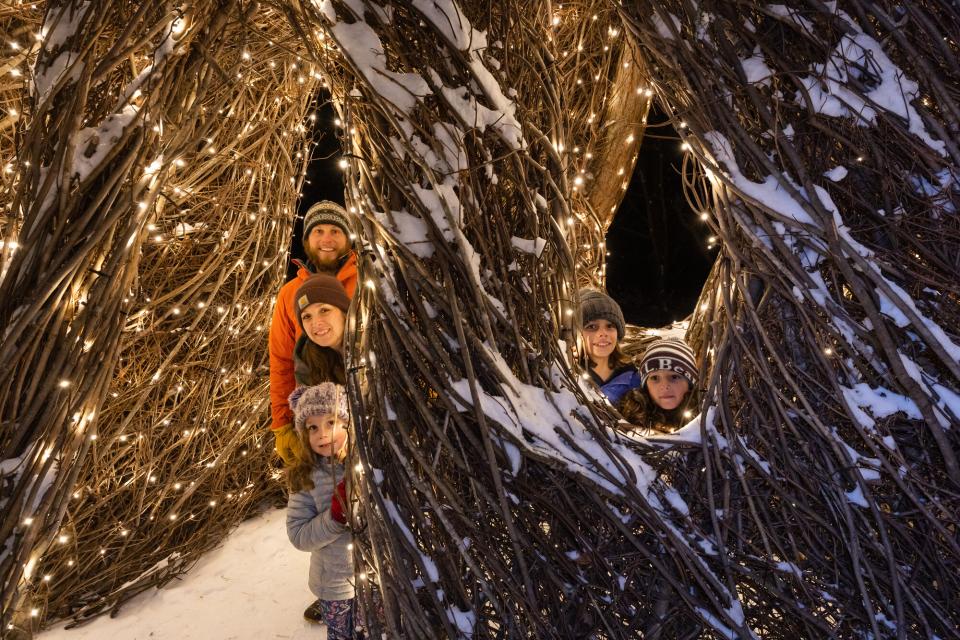 A family poses with a lit up tree art installation.