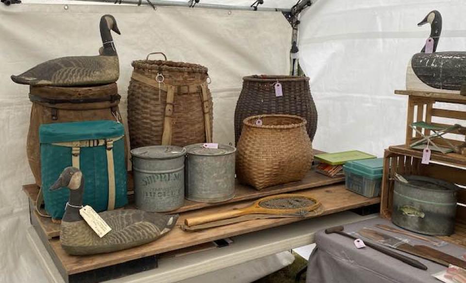 A table of old pack baskets and duck decoys