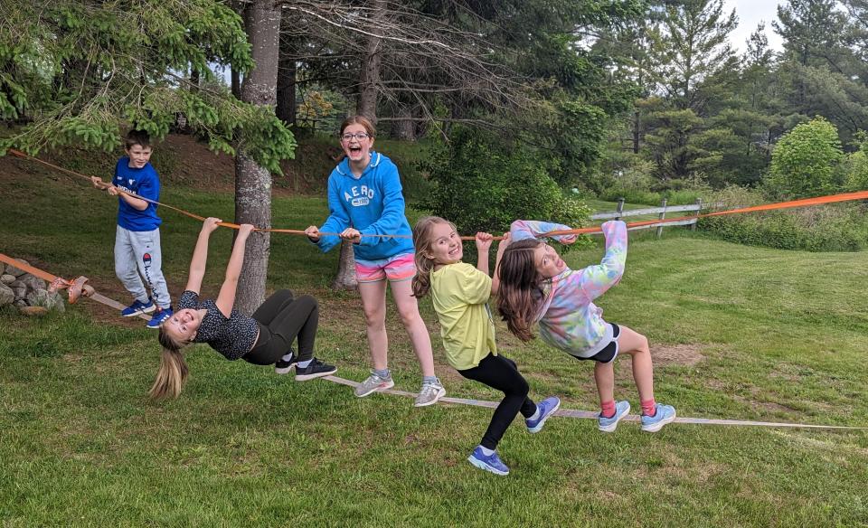 Several children posing while playing on an outdoor slack line