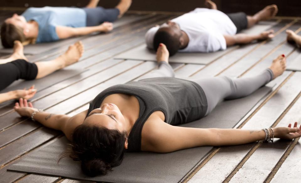 Several people laying on their backs on yoga mats looking relaxed