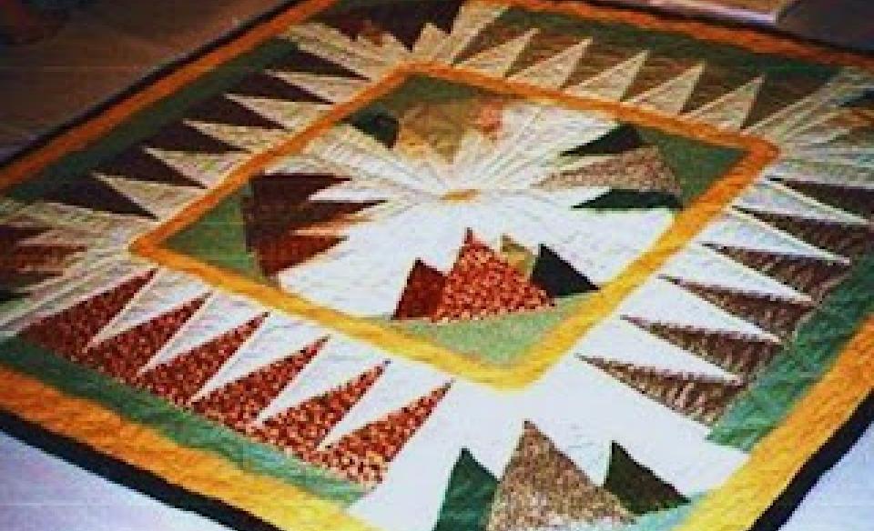 A photo of a adirondack quilt with mountain designs in a square quilt