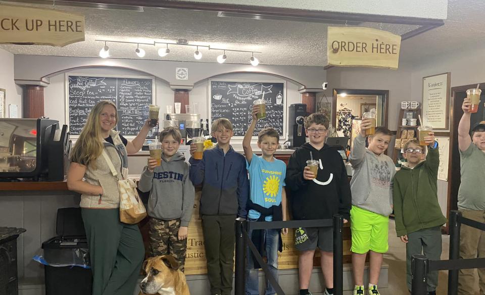 A line of young boys holding up their drinks in front of the counter