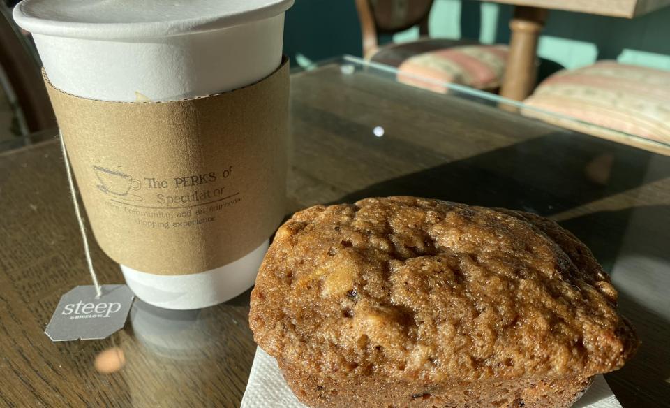 A frothy hot beverage with a mini banana bread loaf next to it