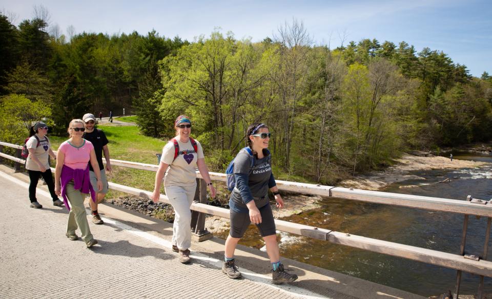 A group of people walking together across a footbridge bridge