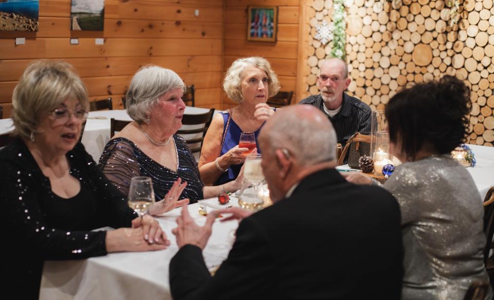 People dressed up, eating and talking around at a table