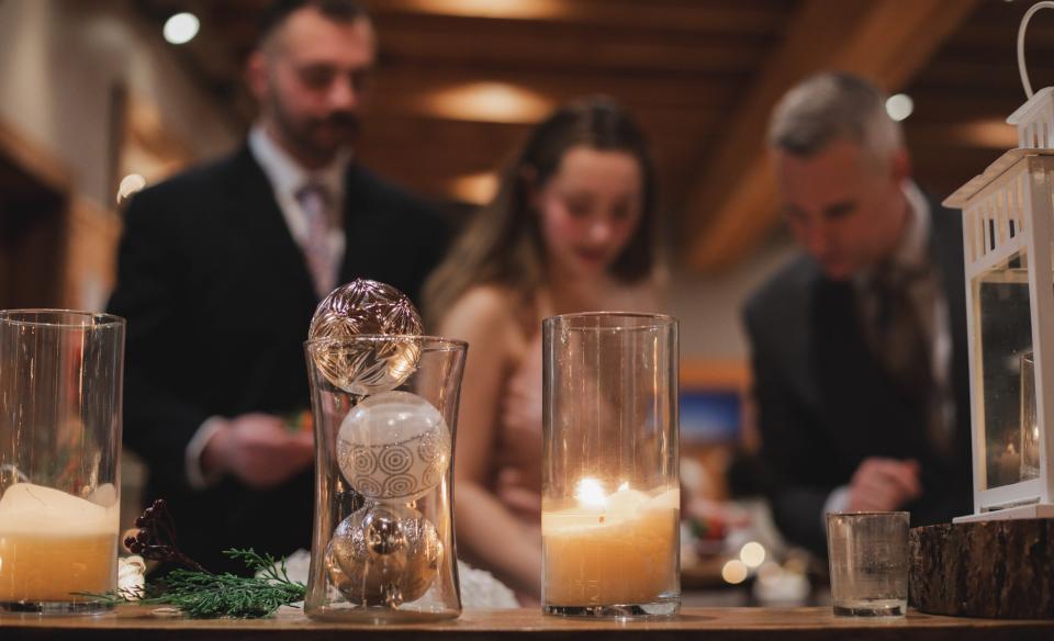 People getting food in the background with the focus of the holiday decorations of candles and glittery ornaments in the foreground of the photo