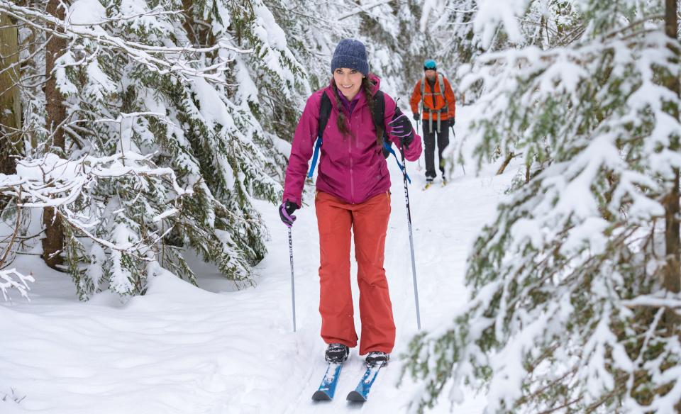 A woman cross-country skiing through the woods after a fresh snowfall