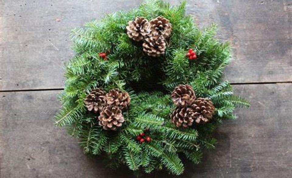 A wreath made from Balsam fir branches and decorated with pinecones and red berries