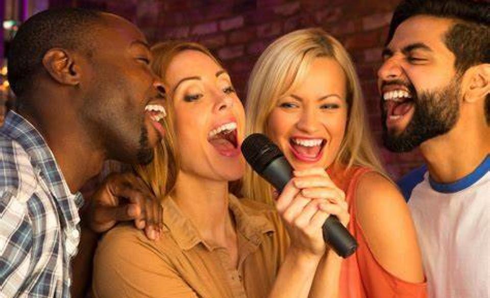 four people singing karaoke in a microphone