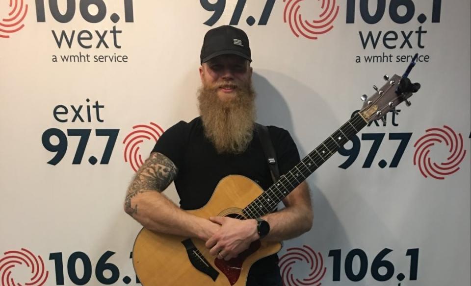 A photo of Josh cleventine holding an acoustic guitar