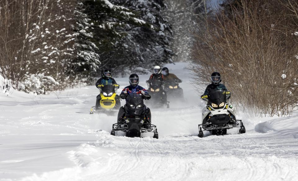 Four snomobiles riding on a trail