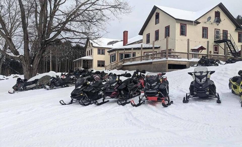 picture of long view lodge in winter with many snow mobiles parked outside