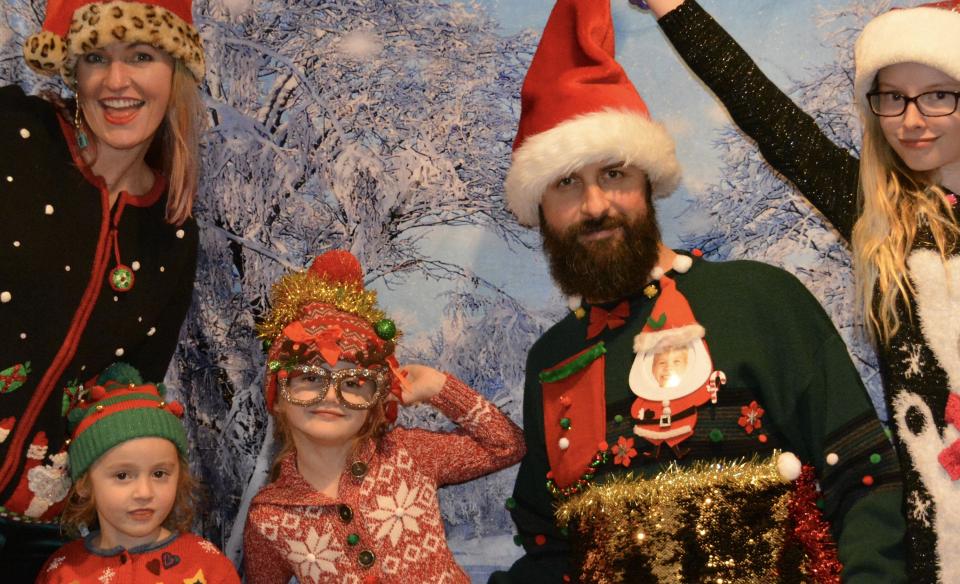 A family all wearing ugly Christmas sweaters and posing for a photo