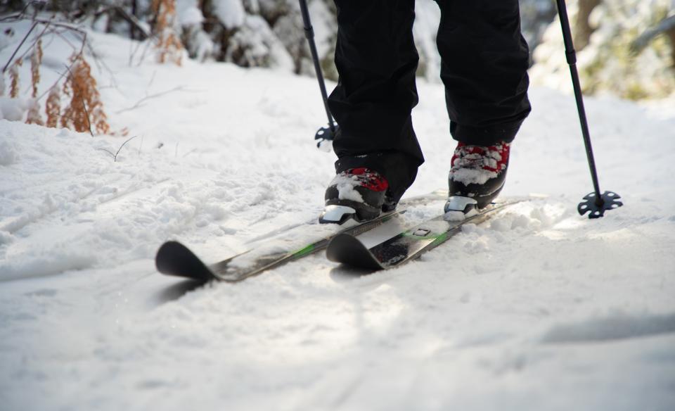 a close up photo of a x-country skiier's feet, skiing in the snow