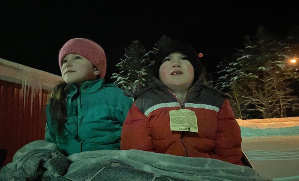 two kids outside looking in awe at the fireworks