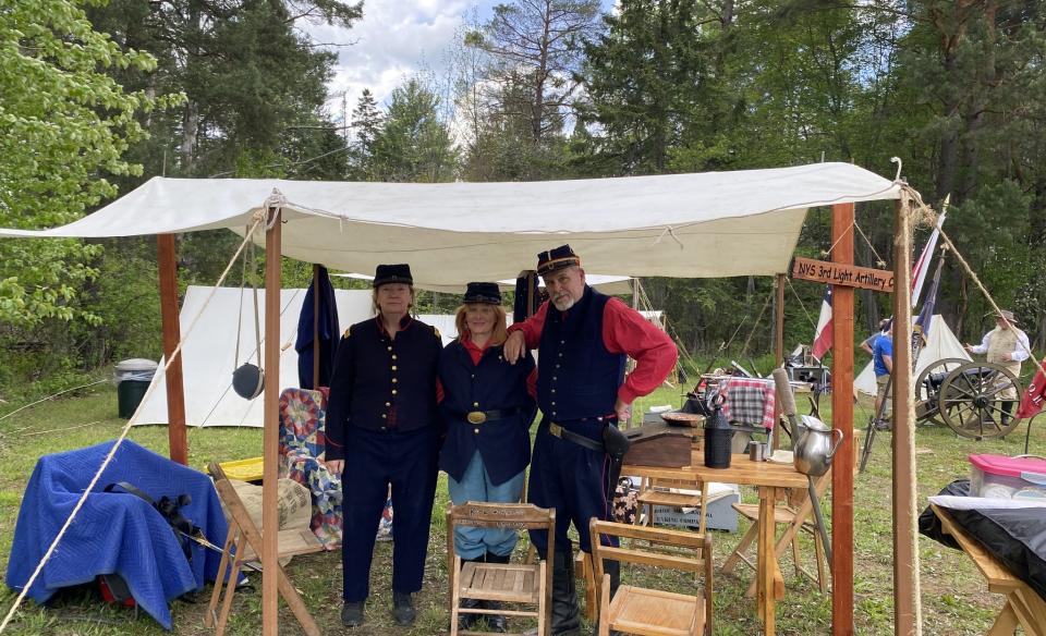 several people dressede in the civil war era standing under a canvas tent