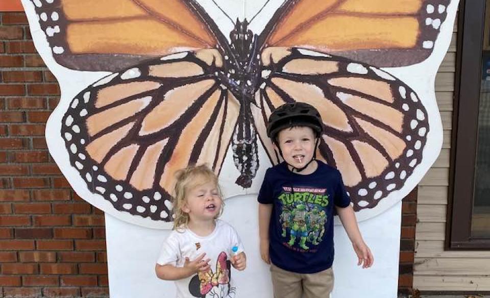 Two children posing in front of the monarch photo prop