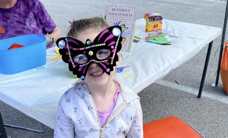 a little girl wearing a butterfly mask that she decorated