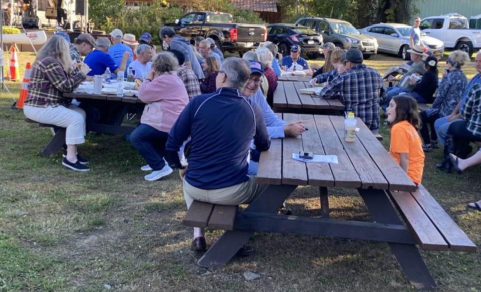 people sitting at picnic tables enjoying the music