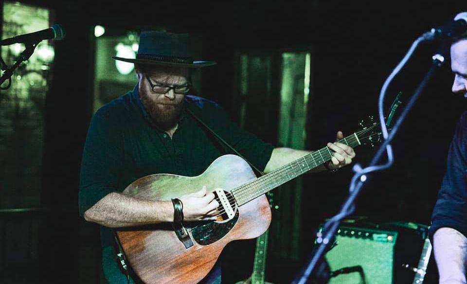 Musician Seth owen Becker playing an acoustic guitar