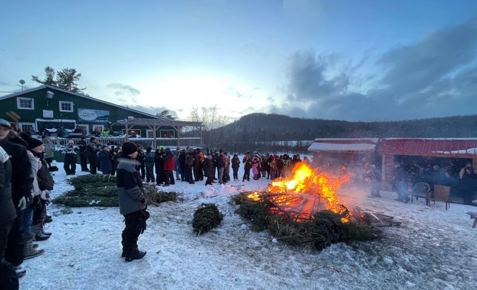 the tree bon fire with a crowd of people circled around with the Oxbow Inn in the background