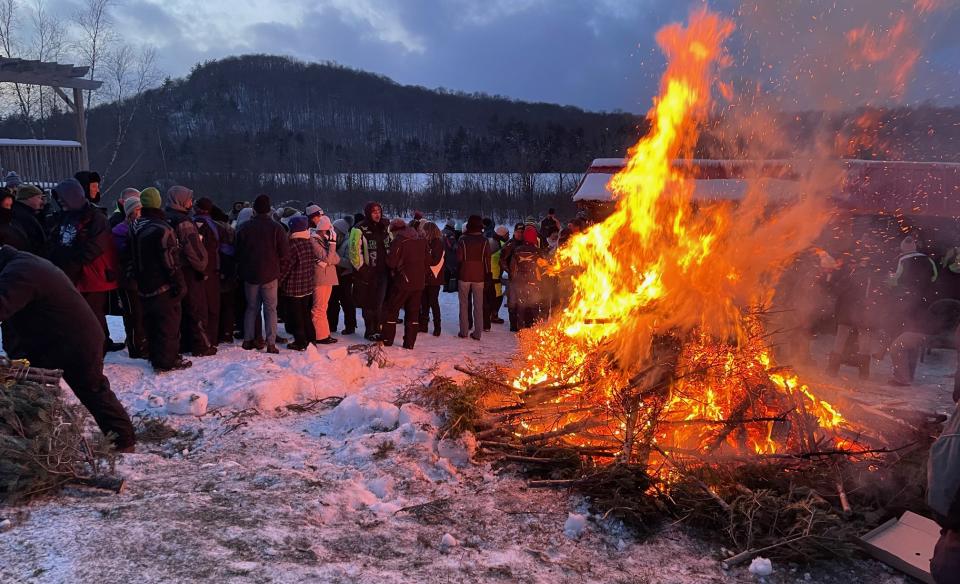 the tree bon fire with a crowd of people circled around