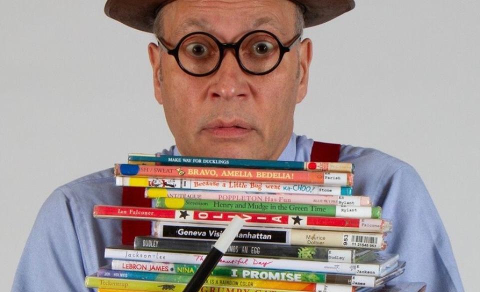 the great and powerful dave magician holding a stack of library books and a magic wand