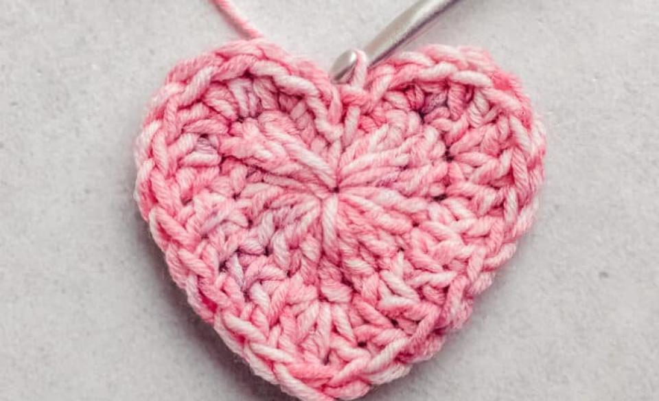 A photo of a crocheted heart with a crochet needle