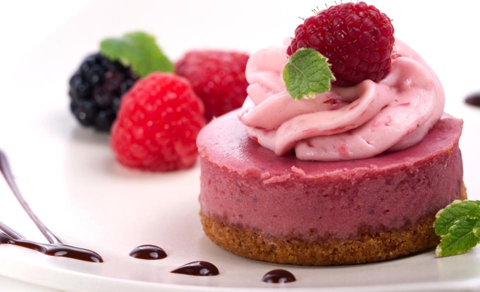 a raspberry cheese cake with pink whipped topping and a raspberry garnish