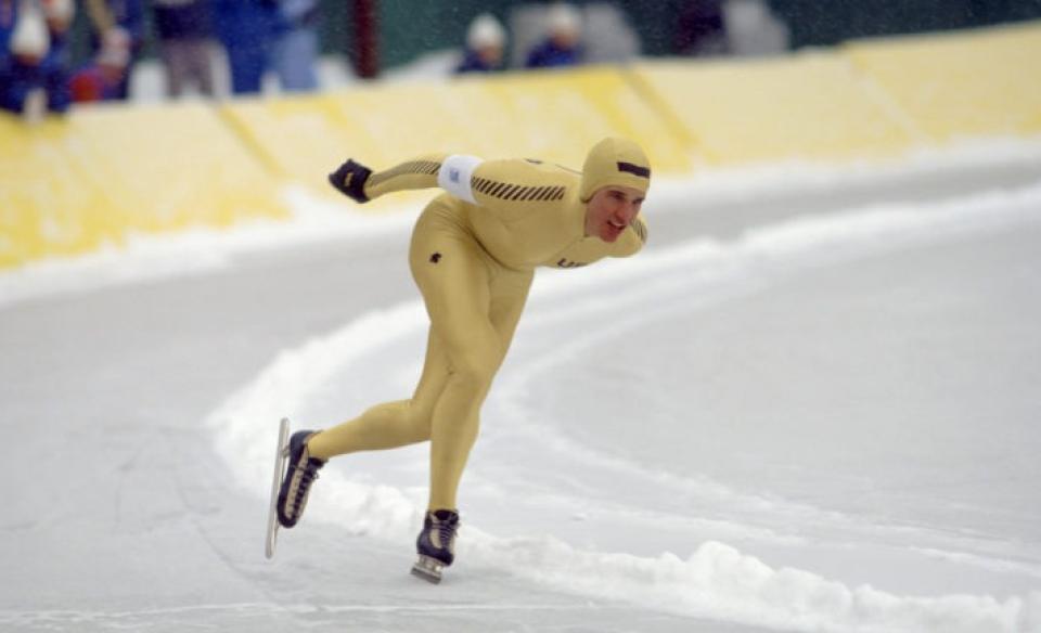 A man is a speedskating uniform racing around an ice track