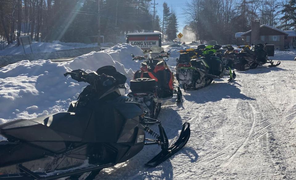 A line of snowmobiles parked outside of the long lake lodge