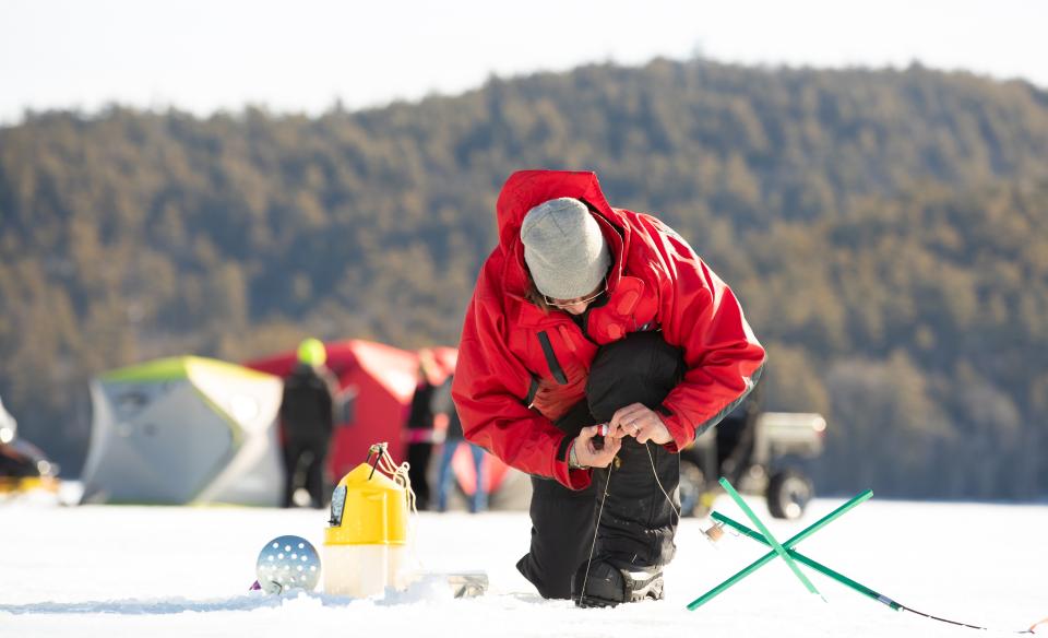 Man setting up his tip up for an ice fishing derby on a frozen lake.