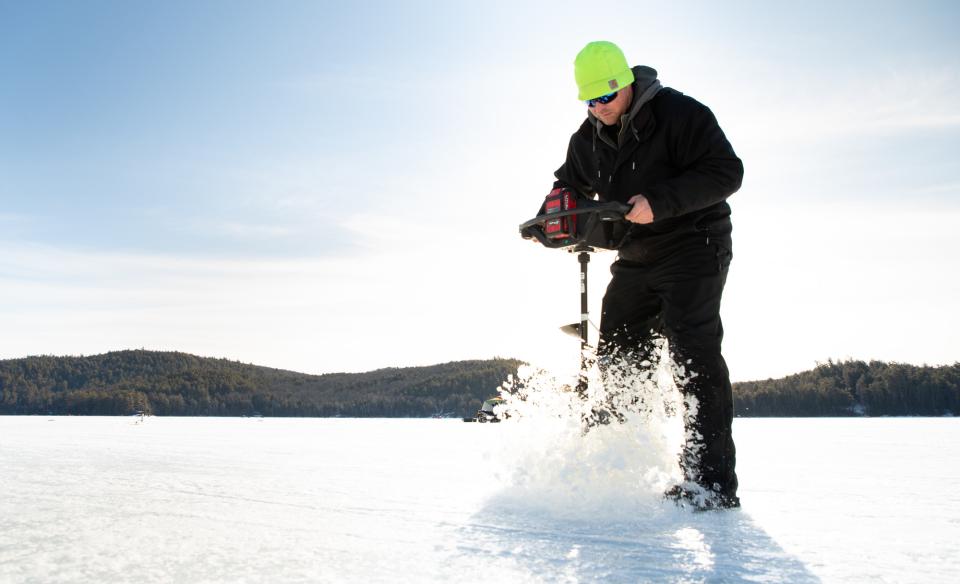 Man using an ice auger on a frozen lake.