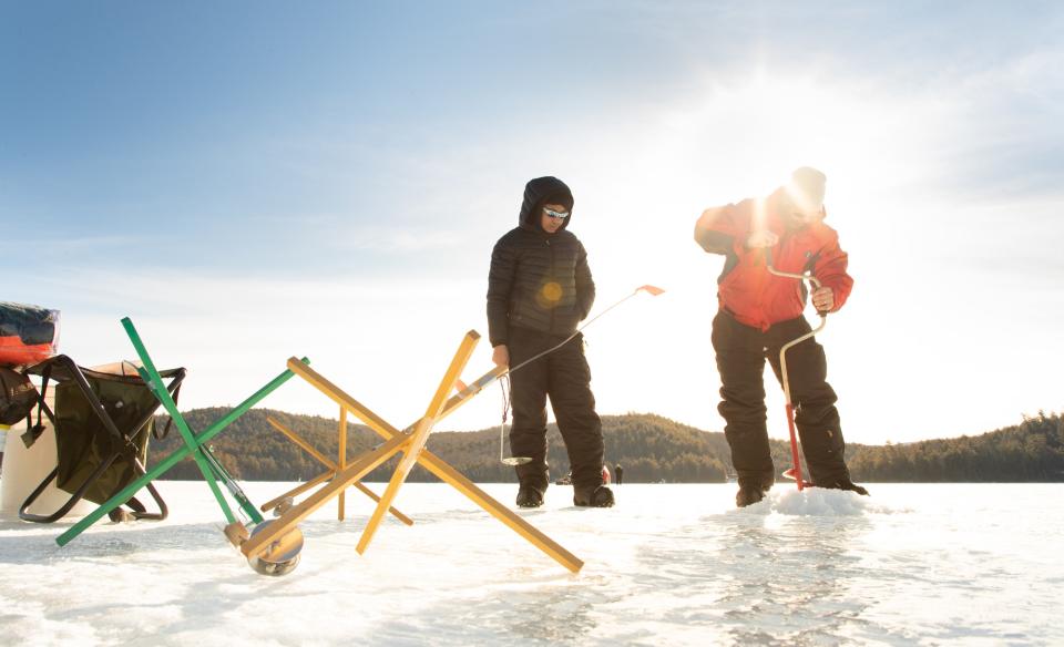 Two ice fishermen setting up gear on a frozen lake.