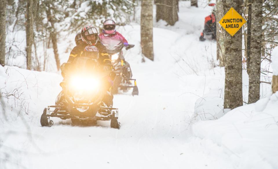 a family riding snowmobiles on a trail