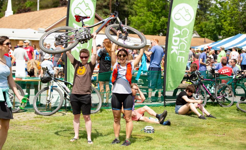 A woman in cycling gear rides a bike on a dirt trail in a forest during the Black Fly Challenge.
