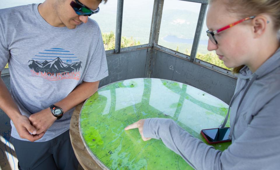 Two hikers in a firetower looking at a table-top map