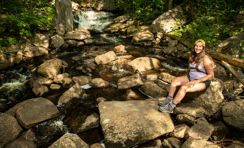 A woman poses by Whiskey Brook Falls