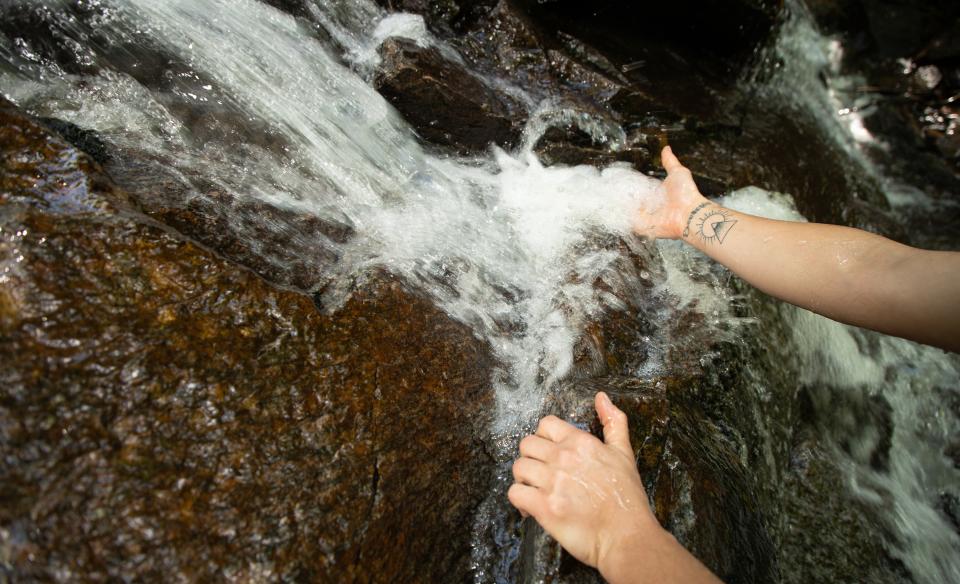 A person lets a brook's water flow through their hand