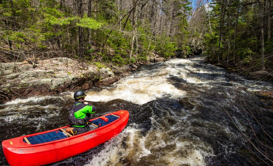 A whitewater kayaker heads towards some rapids.