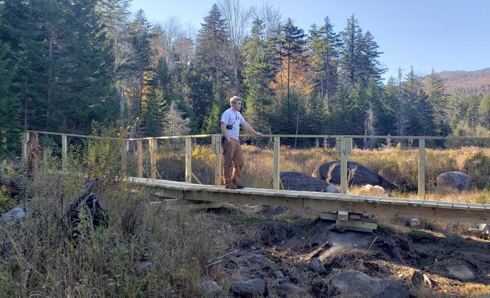 A hiker standing on a wooden bridge