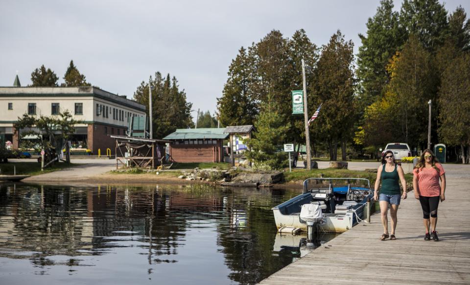 Two people on a dock next to a boat launch