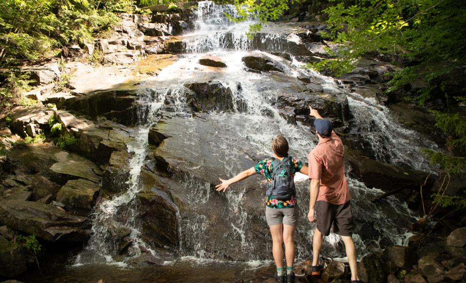 Two people in front of a fanning waterfall