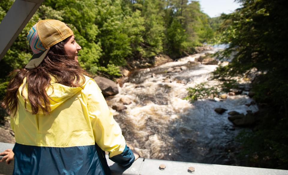 A woman looks out from a bridge over the Sacandaga River during her hike to Griffin Falls