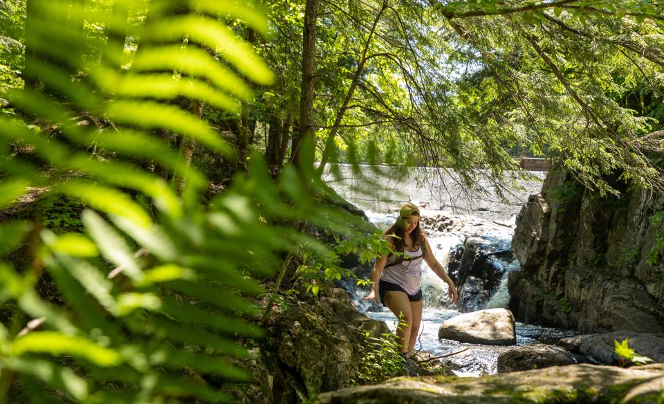 A woman walking in front of a waterfall