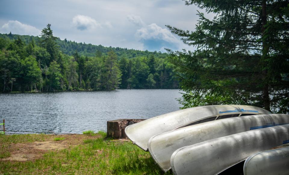 A few aluminum canoes next to the water.